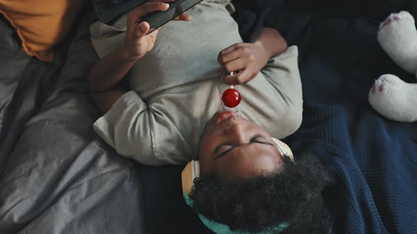 Boy Using Smartphone and Having Lollipop