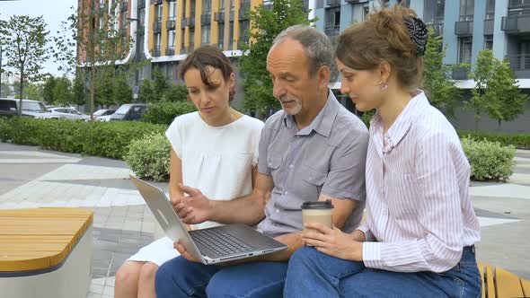 Senior Businessman Mentor or Coach is Teaching an Interns Pointing at Laptop Screen Helping New