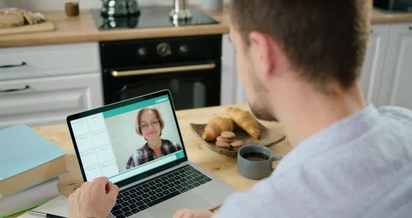 Male Student Study Online By Video Lesson with Teacher Using Laptop in Kitchen