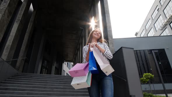 Smiling Girl Walking From Centre Mall with Shopping Bags, Happy with Purchase on Black Friday