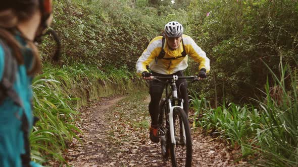 Man riding bike while woman cheering in the forest