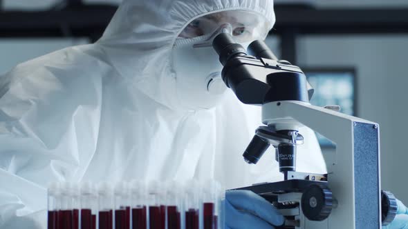 Scientist in protection suit and masks working in research lab using laboratory equipment.