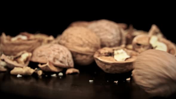 Whole Walnut Rolls in Slow Motion Against a Background of Pile of Nuts in a Loop