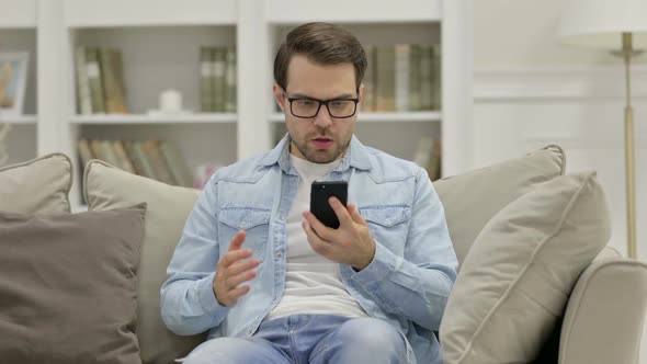 Upset Young Man with Loss on Smartphone at Home