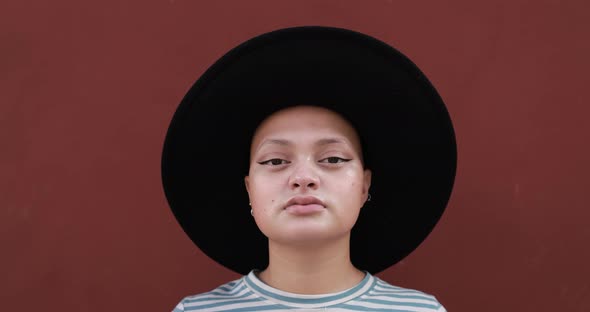 Trendy bald girl looking on camera while wearing a hat