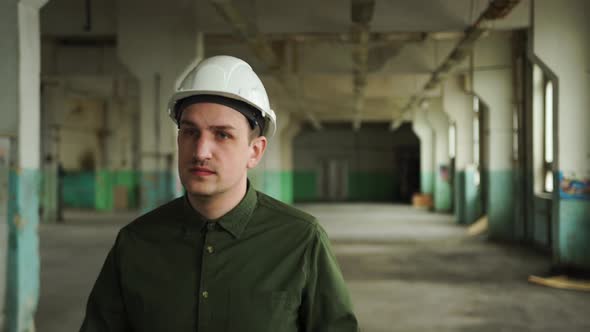 Inspector in Helmet Walks Along the Corridor of an Old Building Looks Around