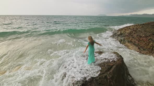 Woman Walks on Rock of Sea Reef Stone Stormy Cloudy Ocean