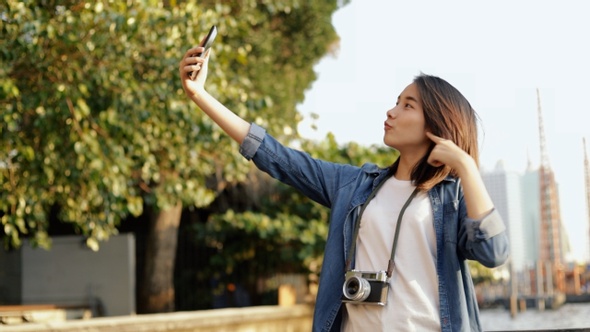 Beautiful Asian woman taking selfie video chat with her friends sharing enjoyment vacation.