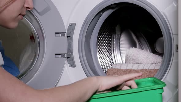 Woman puts a capsule of washing powder in the washing machine