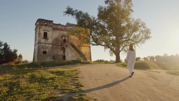 Girl dressed in white goes to a ruined castle in the countryside