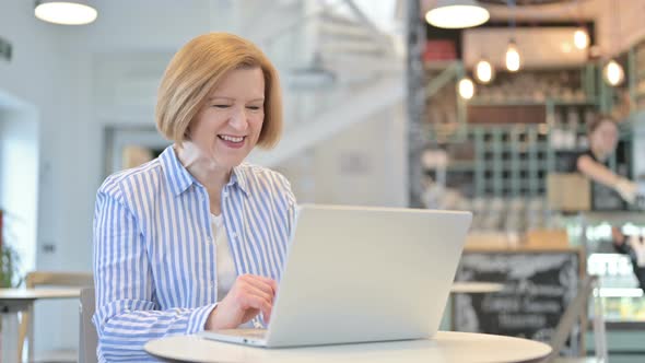 Video Chat on Laptop By Creative Old Woman in Cafe 