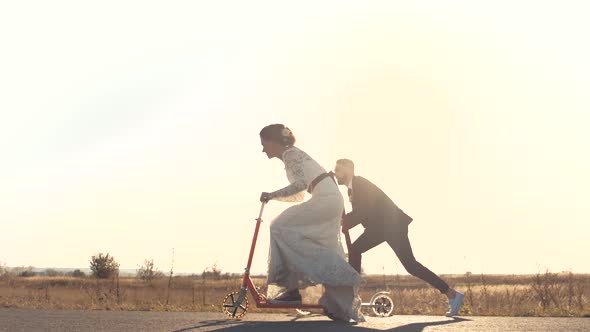 Young Couple Ride a Scooter in Road at Sunset