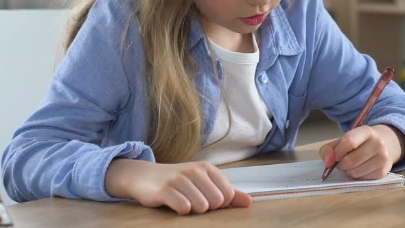 Concentrated School Girl Doing Homework Exercise in Notebook, Home Schooling