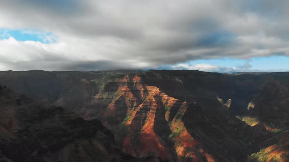 Drone camera shoots cloudy sky touching the peaks of mountain range in Waimea Canyon, Kauai, Hawaii