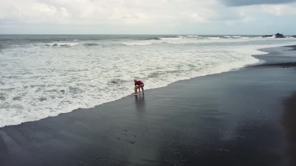 Man Walking on Black Sand Beach Before Storm