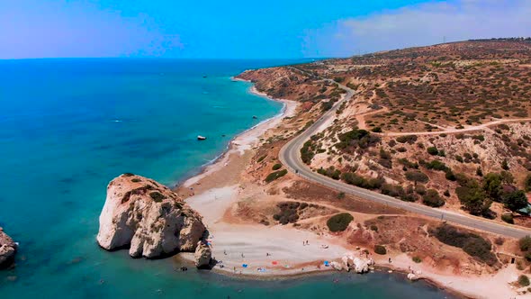 Aerial shot of tourists on the beach near Aphrodite's Rock on the coast of Paphos Cyprus