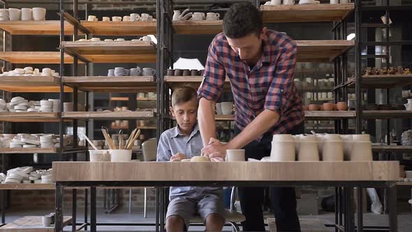 Caring Male Potter Teaching His Son How Kneading Clay for Pots 