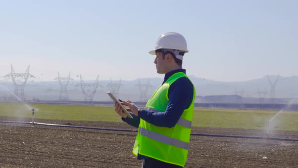 Engineer works with tablet in farmland.