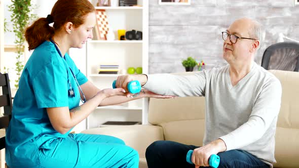 Female Nurse Helps an Old Man To Make His Morning Exercises