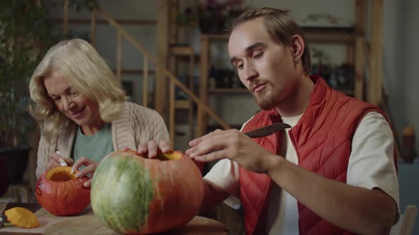 A Young Man with His Mother Draws on Pumpkins and Carves Faces on Them