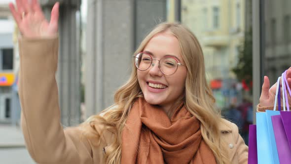 Closeup Attractive Girl Waving Hand on Street Invites to Shopping Pointing to Bags Woman Showing