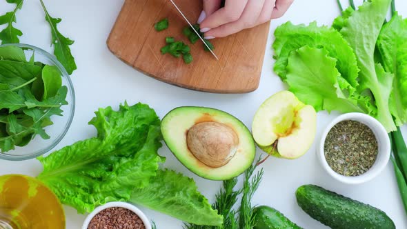 Woman Cooking Salad of Fresh Green Vegetables and Herbs