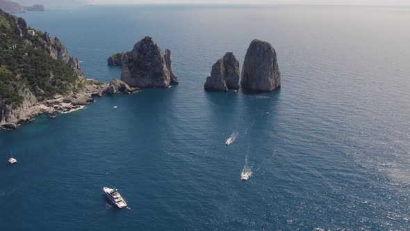 Iconic sea stacks (Faraglioni) off Capri coast, Bay of Naples, Italy; drone