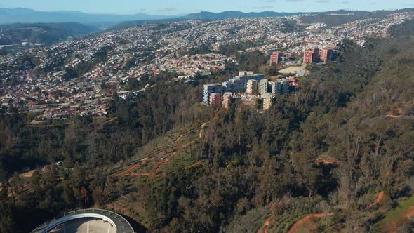 Aerial dolly in of Quinta Vergara Amphitheater, colorful buildings and fall forest park in Viña del