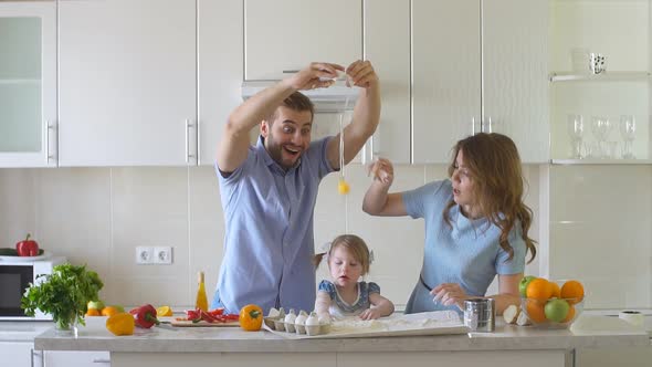 Happy Family Is Cooking in The Kitchen. Daddy Breaks the Egg Slow Motion