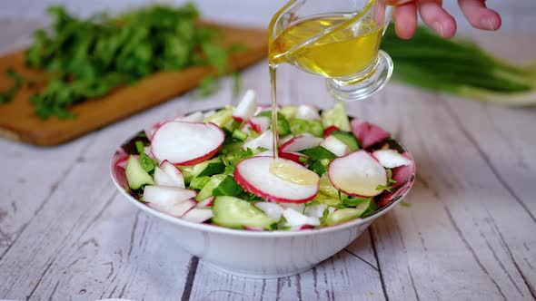 Hands Chef Pouring Olive Oil in a Vegetable Salad with Radish Cucumber Greens