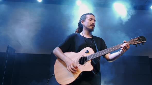 The Singer Plays an Acoustic Guitar at a Concert