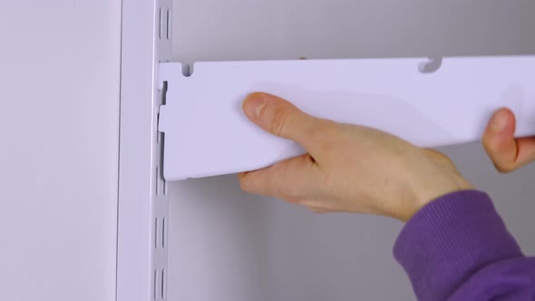 Installation brackets of a metal mesh shelf in the dressing room system on a bracket. Hands is assem