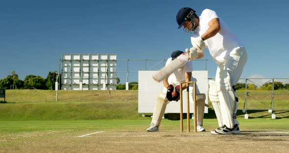 Wicket keeper collecting cricket ball behind stumps on cricket field
