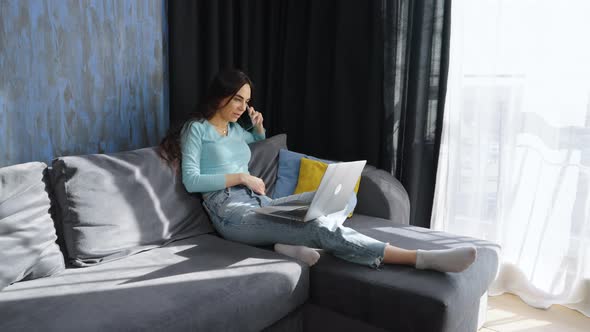 Woman Sitting on Sofa and Talking on Phone