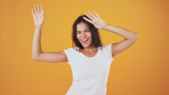 Female is Smiling and Dancing While Posing Over Orange Background