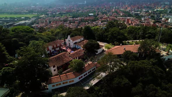 Large residential property on a hill in Medellin surrounded by tall green trees on a sunny day. In t