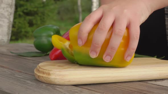 Woman Cuts Pepper in Large Pieces on Wooden Board