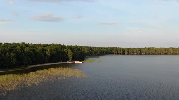 Aerial View of Beach at Lake on a Summer Evening Surrounded by Forest