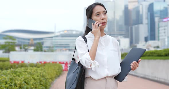 Businesswoman talk to phone and hold with notebook computer