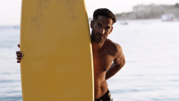Portrait of Young Professional Black Surfer Man Holds His Surfboard in Arm Stands on Ocean Beach