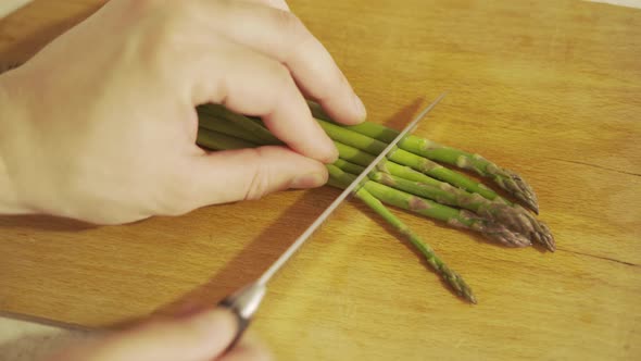 Cutting Asparagus with a Knife on a Wooden Board