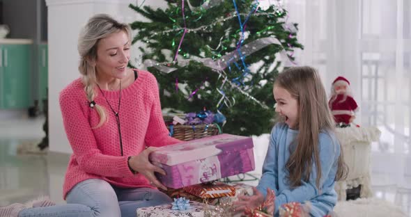 Young Caucasian Attractive Woman Giving Christmas Present To Cute Girl. Mother and Daughter