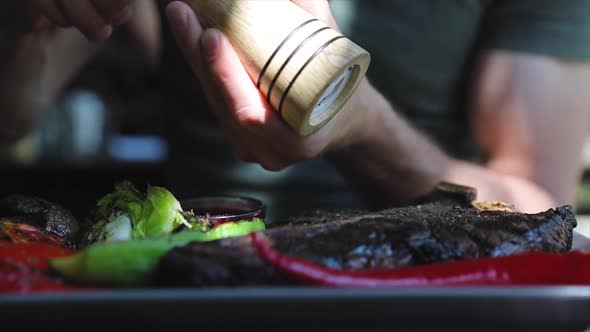 Food Closeup. Man Hand Seasoning Steak Meat With Grounded Pepper