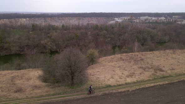 Aerial Shot of Young Sport Men Ride Bicycles on Forest Road at Spring Cloudy Evening