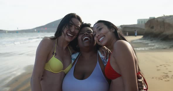 Multiracial women hugging each others on the beach
