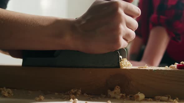 Woman Builder Using Plane for Wooden Board Closeup