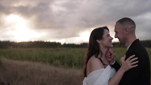 Newlyweds in Love on a Walk in the Countryside Stand Embracing and Look Into Each Other's Eyes