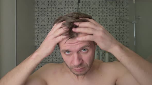 Man in Bathroom Looking at His Thinning Hair