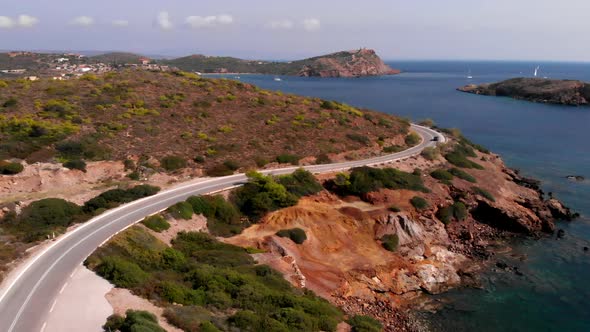 Car disappears behind corner on winding road at Cape Sounion, static aerial