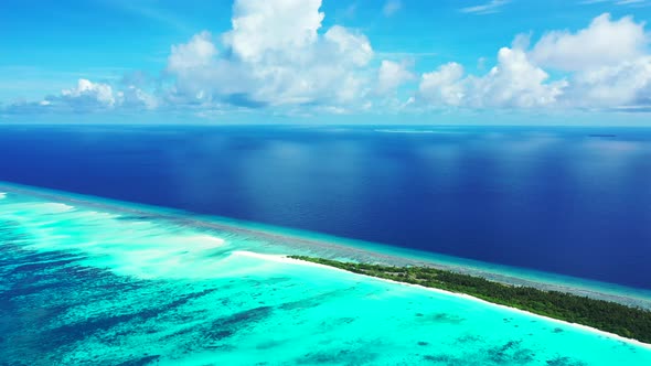 Wide birds eye tourism shot of a sunshine white sandy paradise beach and blue sea background in 4K